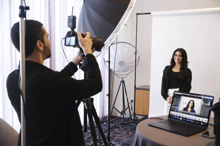 The booth set up in a hotel meeting room: lights, a white backdrop and a tethered laptop.